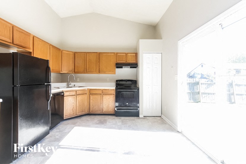 an empty kitchen with wooden cabinets and black appliances