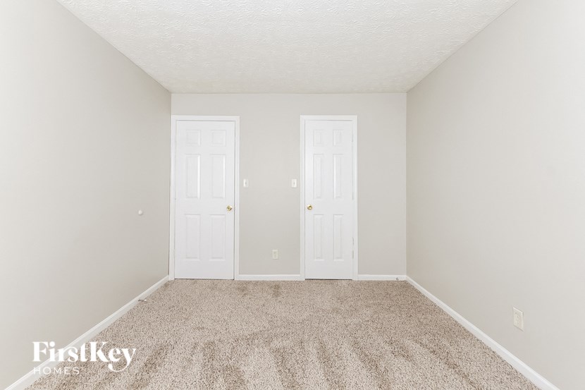 a bedroom with two doors and a carpeted floor