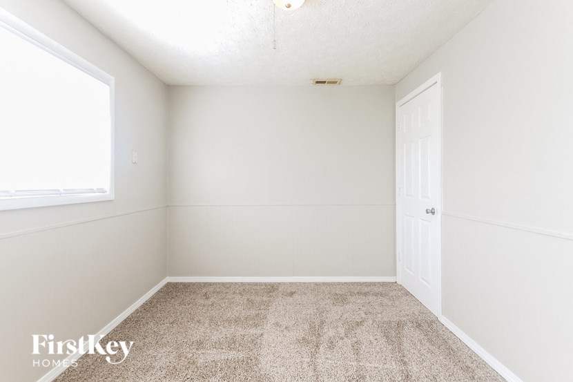 a empty room with white walls and carpet and a window