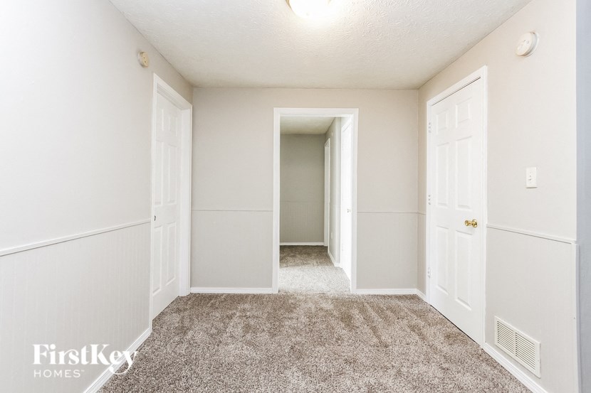 a bedroom with white walls and carpet and a door to a closet