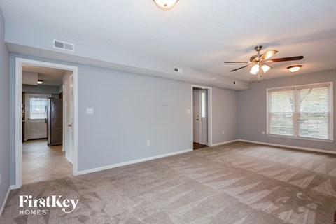 A spacious room with a carpeted floor and a ceiling fan.