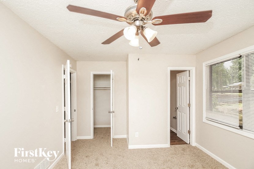 a bedroom with a ceiling fan and a door to a closet