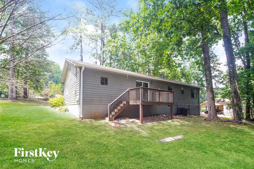 a small house in the woods with a lawn and a deck