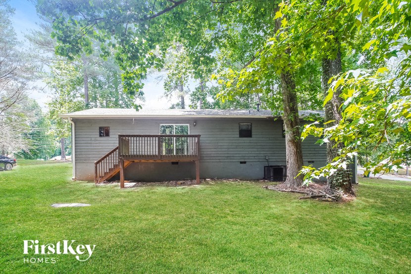 a small gray house with a deck under a tree