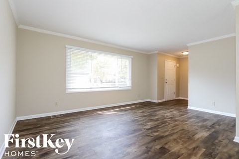 A room with wooden flooring and a window with blinds.