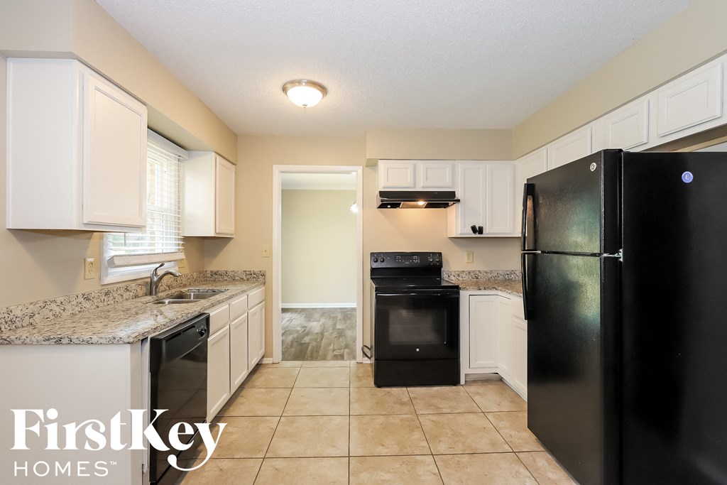 A kitchen with black appliances and white cabinets.