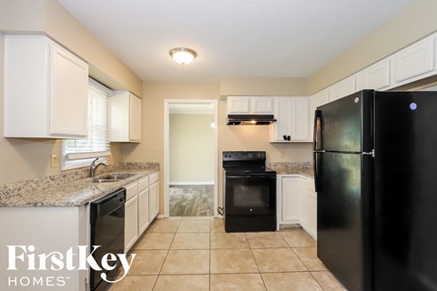 A kitchen with black appliances and white cabinets.