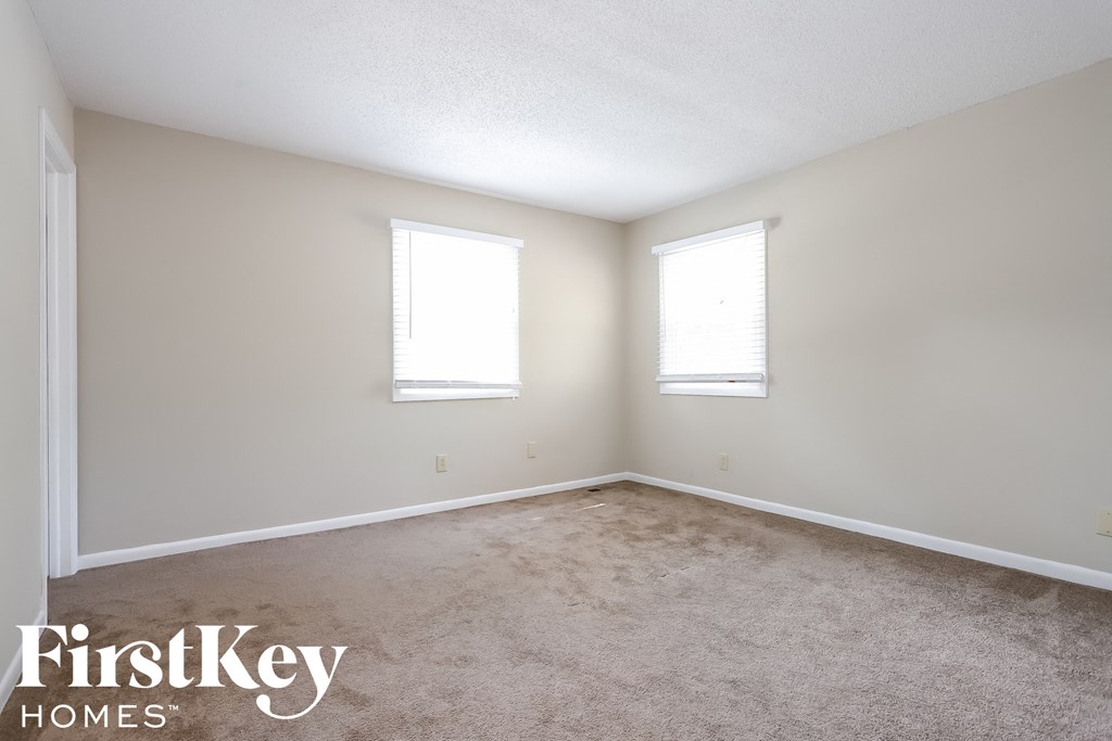 A room with two windows and a carpeted floor.