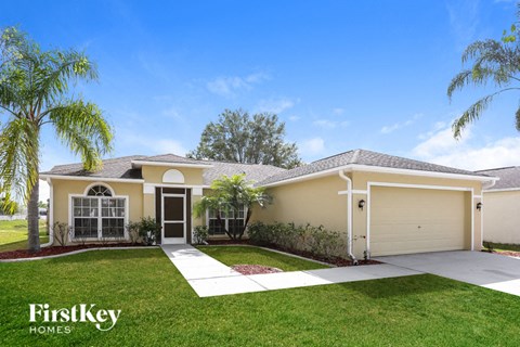 a yellow house with a lawn and palm tree