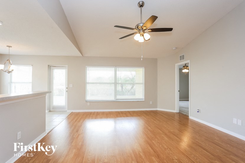 an empty living room with wood floors and a ceiling fan
