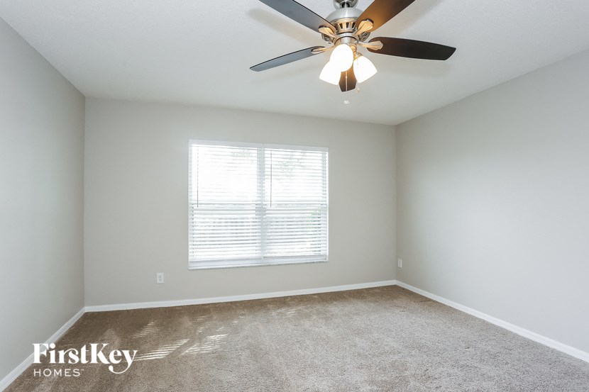 an empty room with a ceiling fan and a window