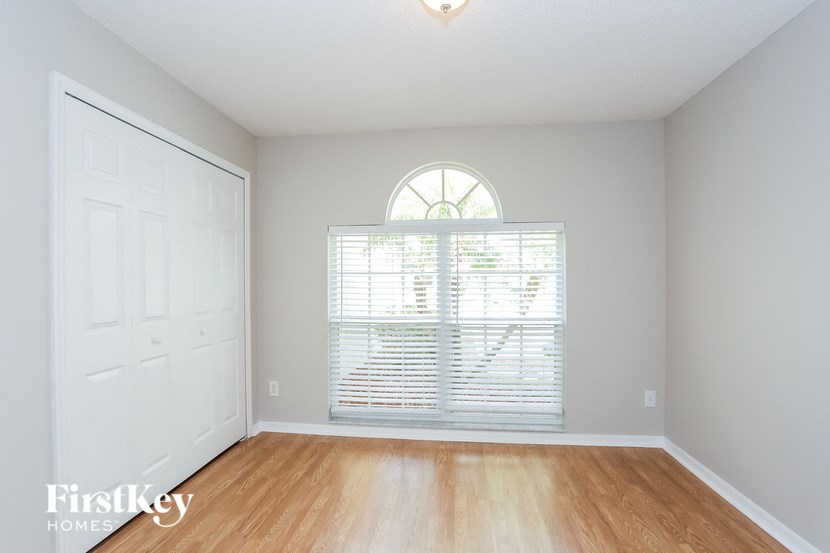 a bedroom with wood floors and a large window
