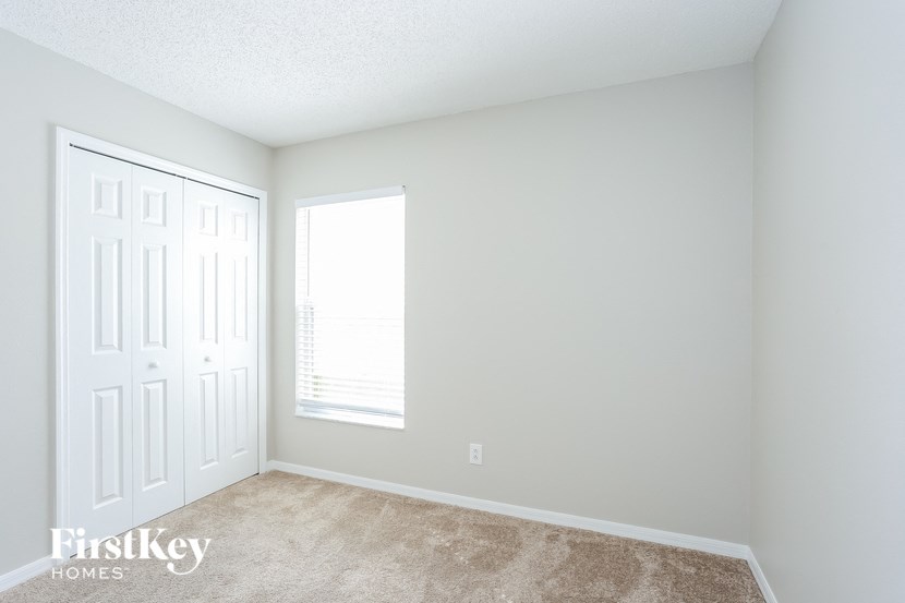 a bedroom with white walls and carpet and a window