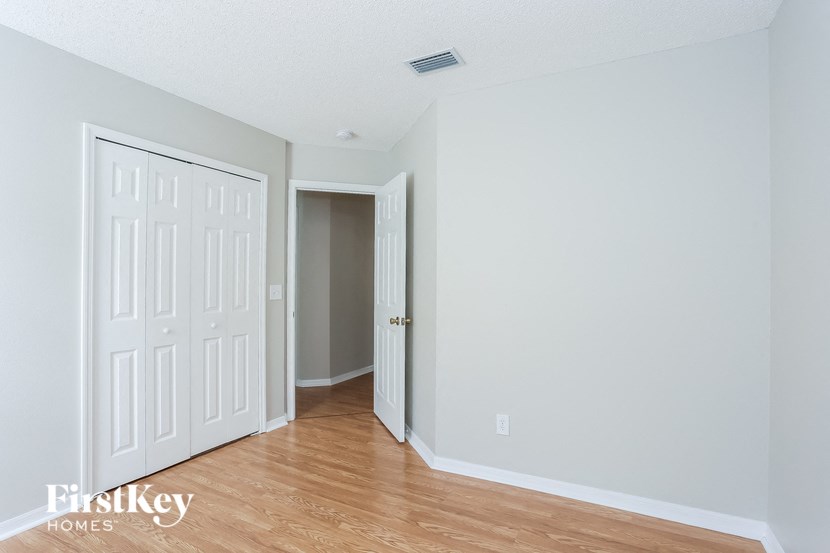 a bedroom with white walls and a wood floor
