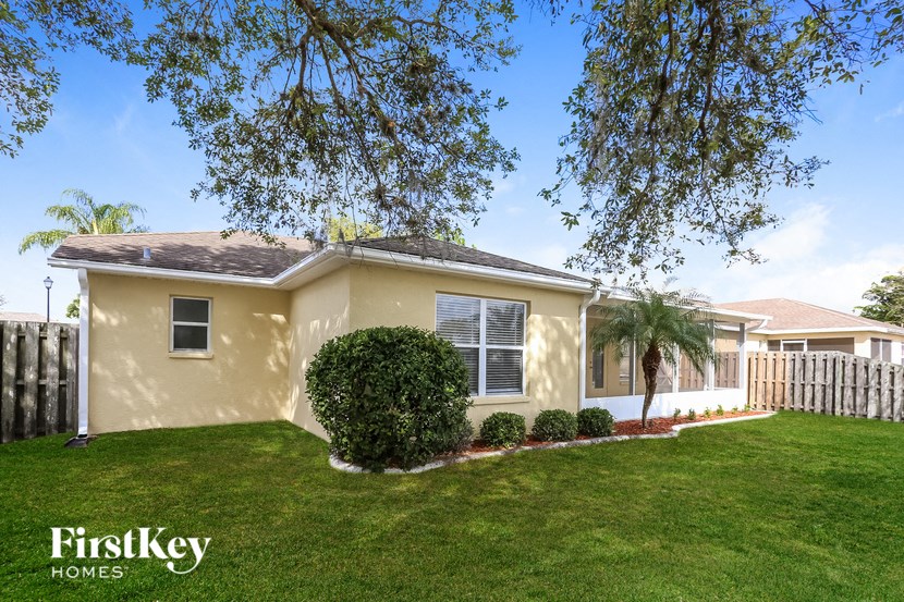 a yellow house with a lawn and a white fence