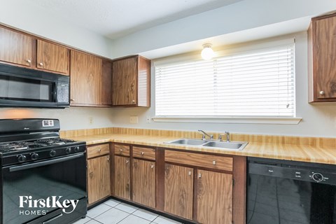 a kitchen with wooden cabinets and black appliances and a sink