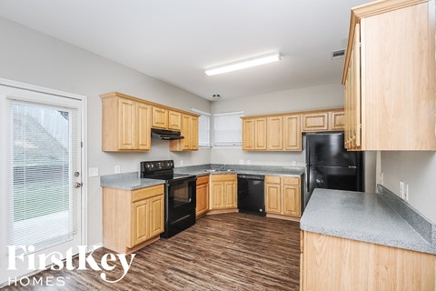 an empty kitchen with wooden cabinets and black appliances