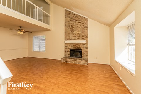 A living room with a fireplace and wooden floors.