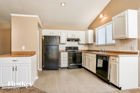 a kitchen with white cabinets and black appliances