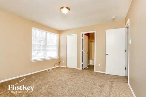 a master bedroom with carpet and a door to a closet and a window