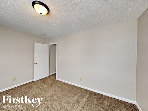 a bedroom with white walls and carpet and a door to a closet