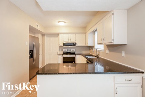 A kitchen with a refrigerator, oven, and sink.