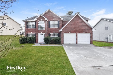 a red brick house with a white garage door and a green lawn