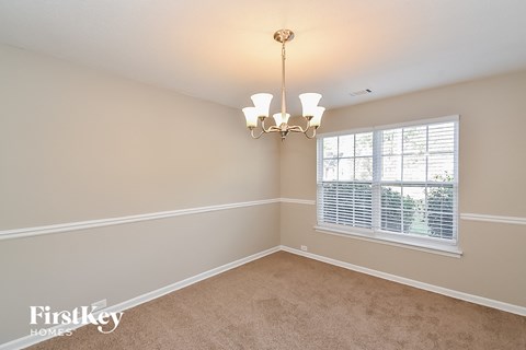 an empty dining room with a window and a chandelier