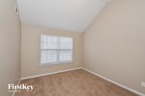a bedroom with beige carpet and a window