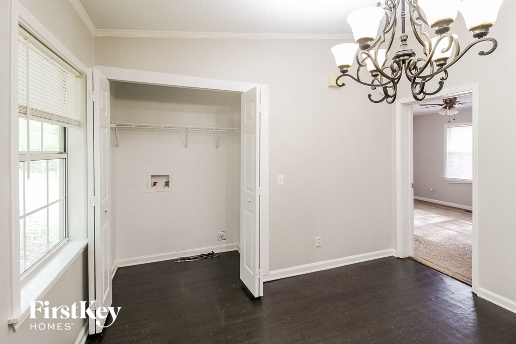 a empty living room with a closet and a chandelier