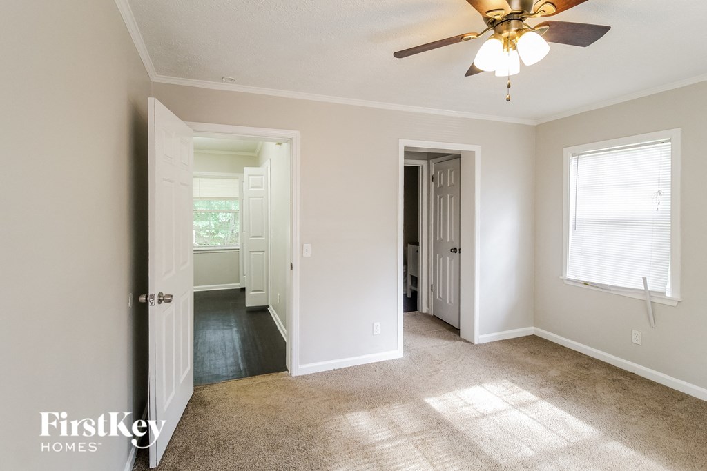 a living room with a ceiling fan and a hallway with a door to a bedroom