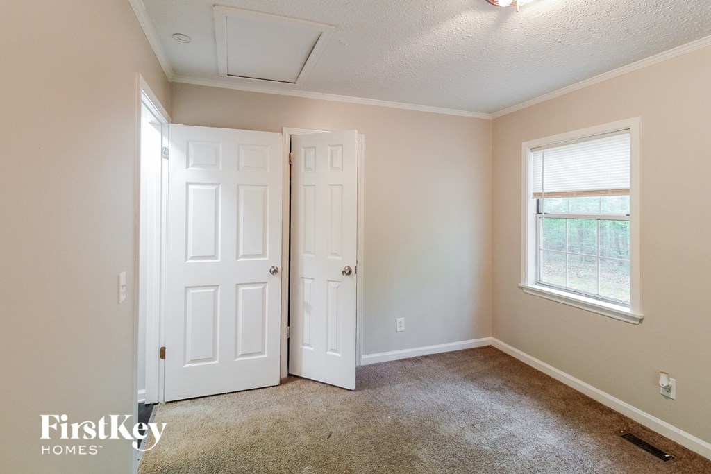 a bedroom with two doors and a window and a carpeted floor
