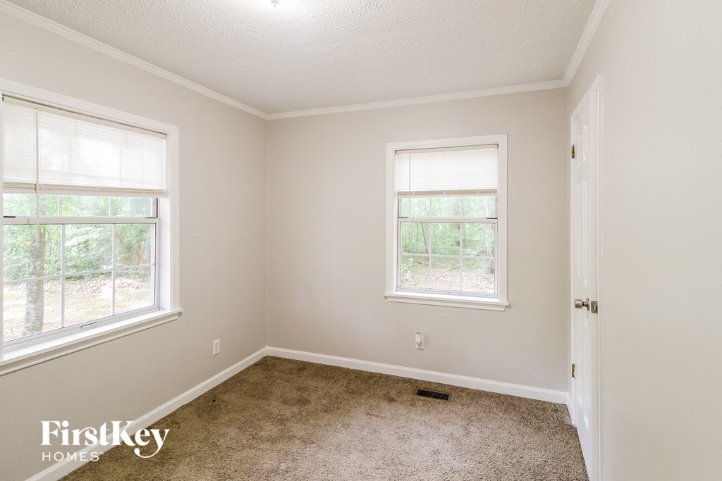 a empty room with two windows and a carpeted floor