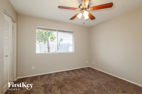 the spacious living room has carpet and a ceiling fan