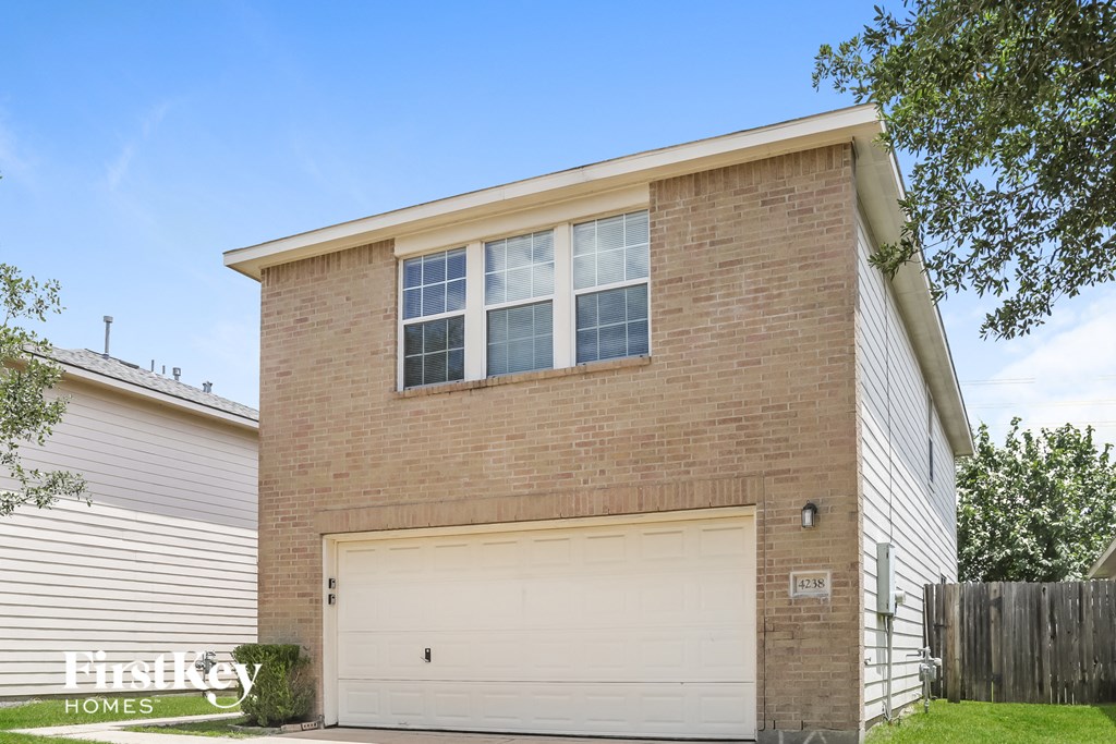 the front of a brick house with a garage door