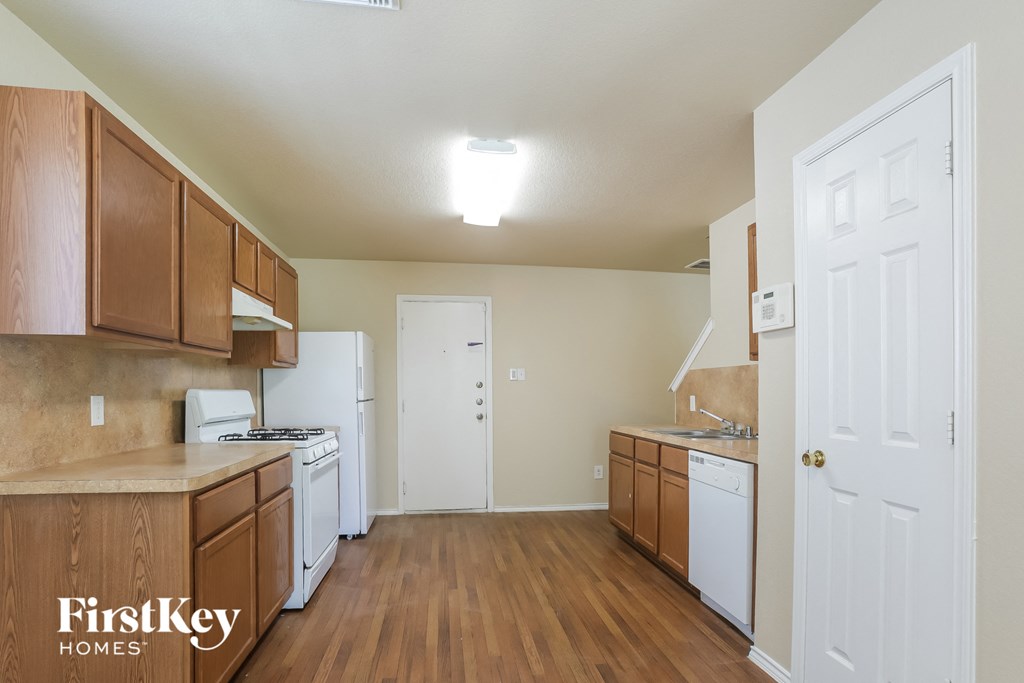 a kitchen with wood flooring and white appliances and wooden cabinets