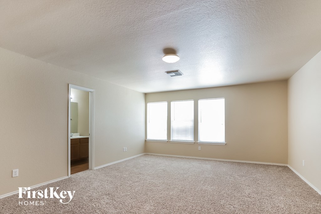 an empty living room with three windows and a ceiling fan