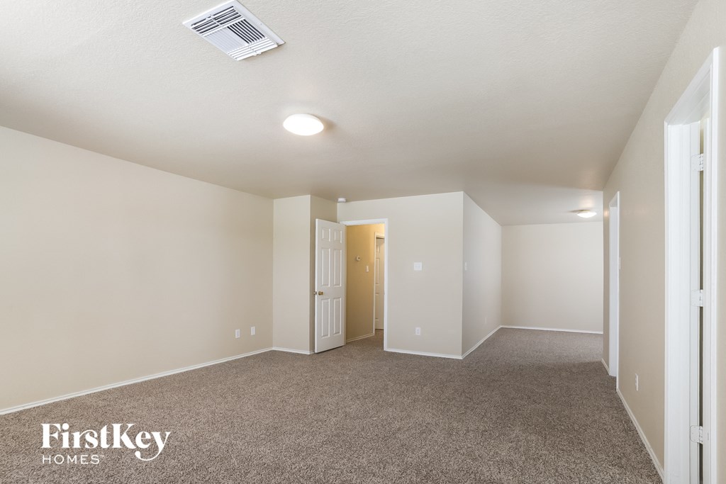 a spacious living room with carpet and white walls