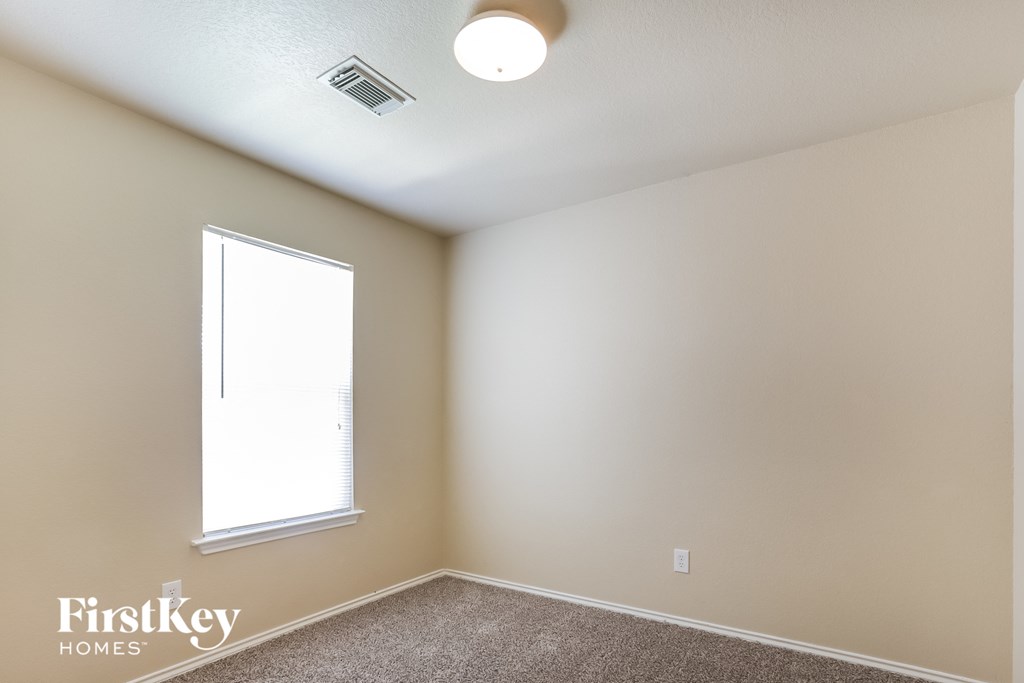 the upstairs bedroom has a large window and carpeted flooring
