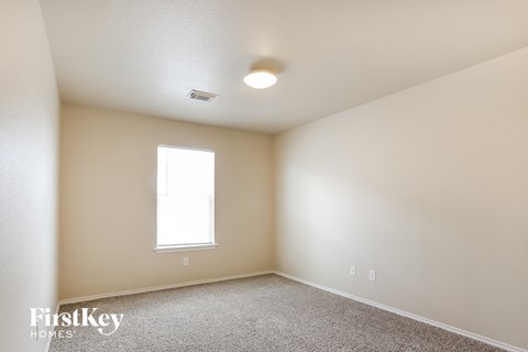a bedroom with white walls and carpet and a window