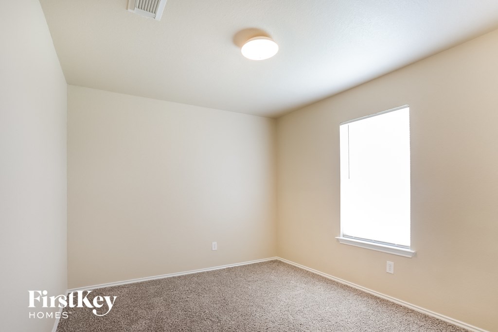 a bedroom with white walls and a window