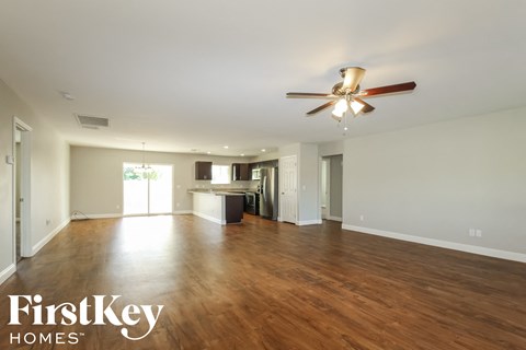 A spacious room with wooden floors and a ceiling fan.