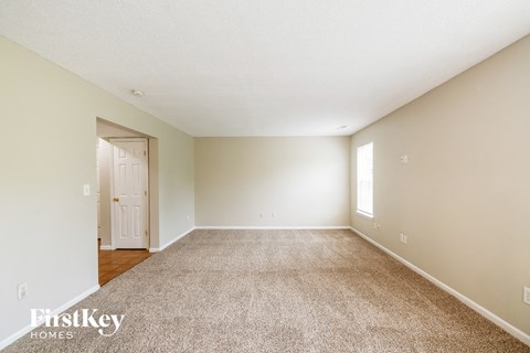 a spacious living room with carpet and white walls