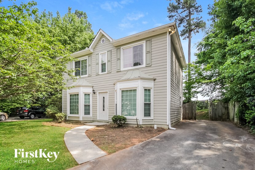 a white house with green shutters and a driveway