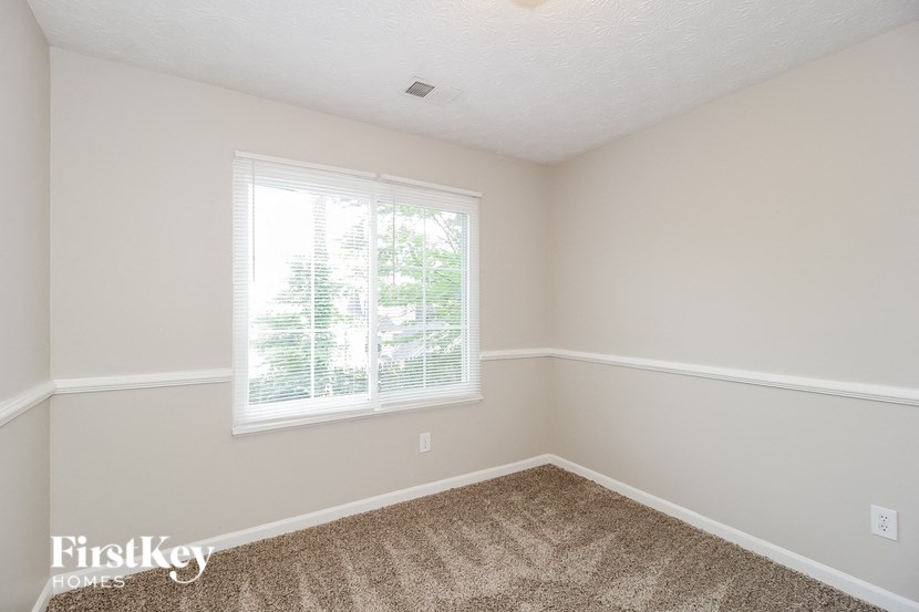 a bedroom with a window and a carpeted floor
