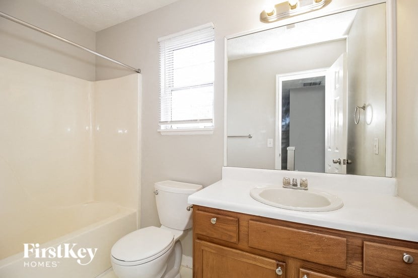 a bathroom with a toilet sink and mirror and a shower