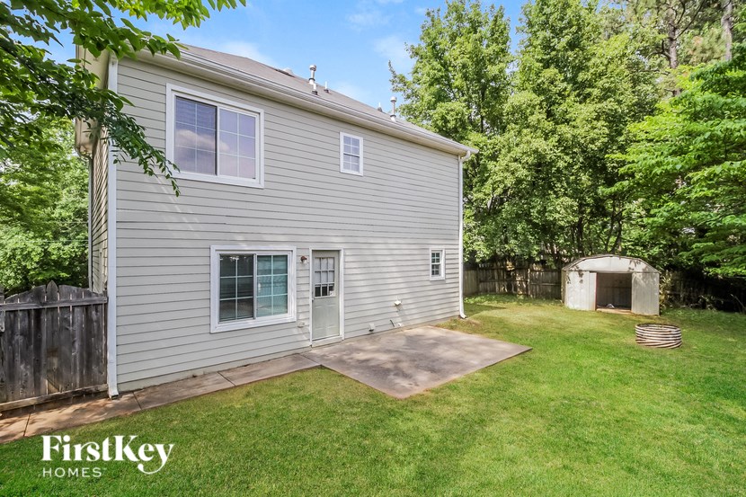 a backyard with a gray house and a yard with a driveway and a garage door