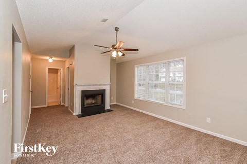 an empty living room with a fireplace and a ceiling fan