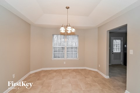 an empty dining room with a window and a chandelier