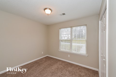 the spacious bedroom has carpeted floors and a large window
